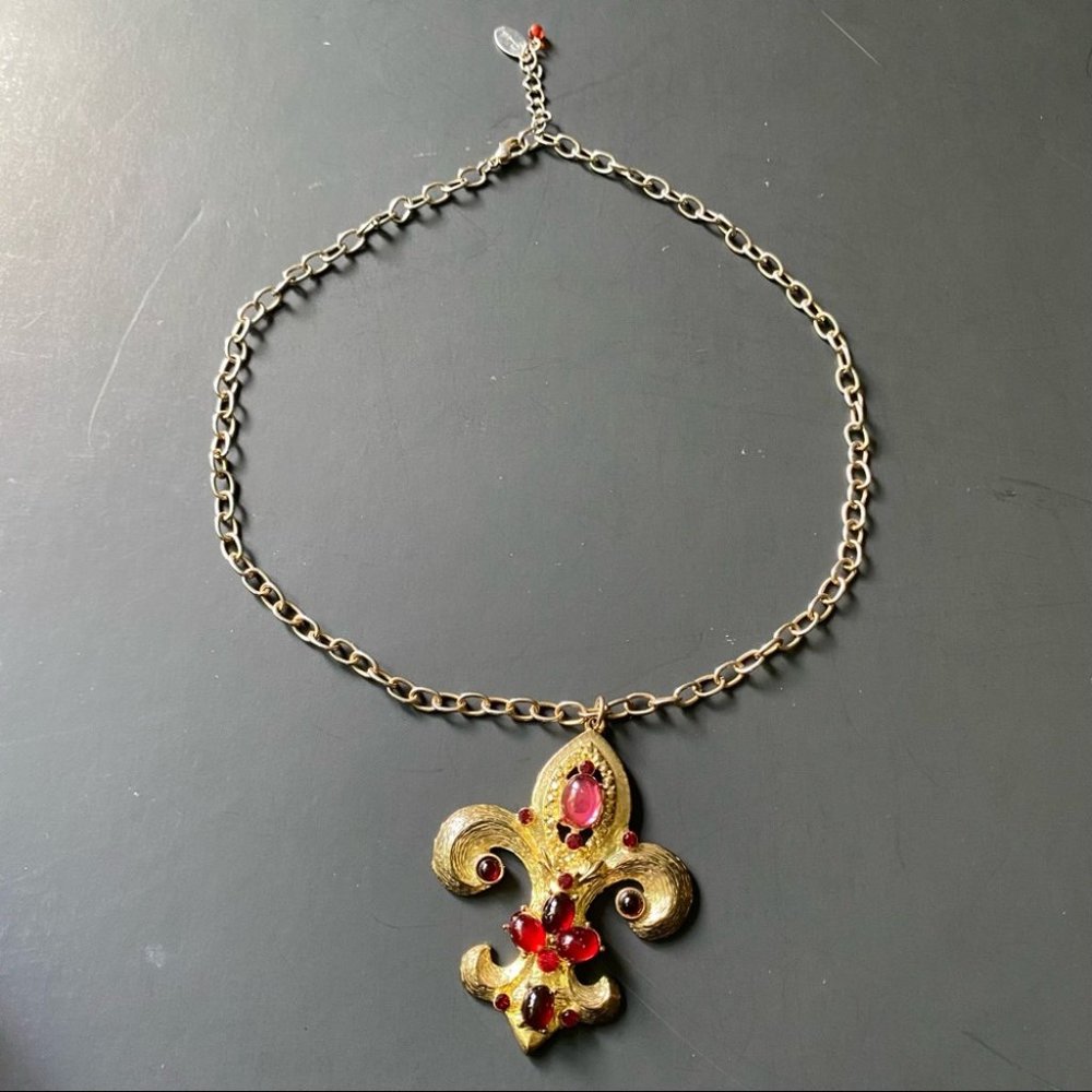 Guess womens Yellow Gold tone Fleur De Lis Pendant with Red rhinestones.